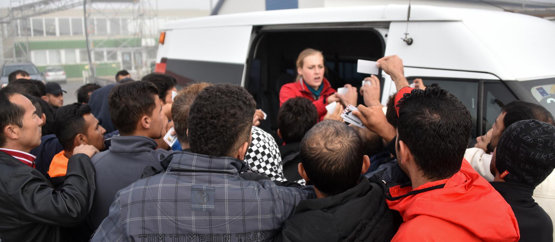 Flüchtlinge in der Erstaufnahmeeinrichtung in Calden stehen vor einem Fahrzeug an