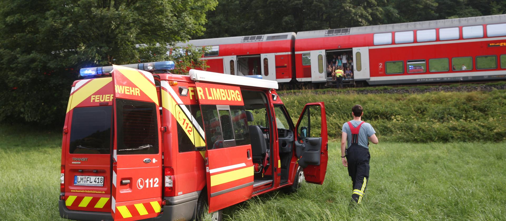 Von einem Baum gestoppt: Ein Regionalzug steht bei Niederbrechen auf freier Strecke. Feuerwehrleute aus Lindenholzhausen betreuen die Passagiere. Bild © hessenschau.de