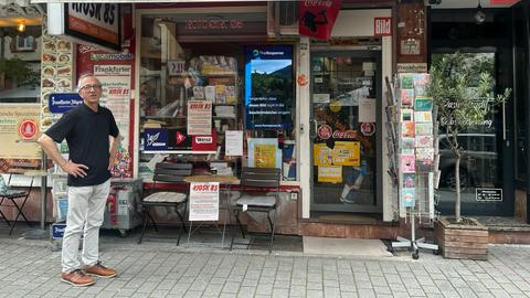 Ein Mann steht neben einem Kiosk und schaut in die Ferne