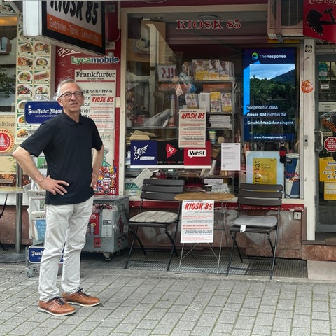 Ein Mann steht neben einem Kiosk und schaut in die Ferne