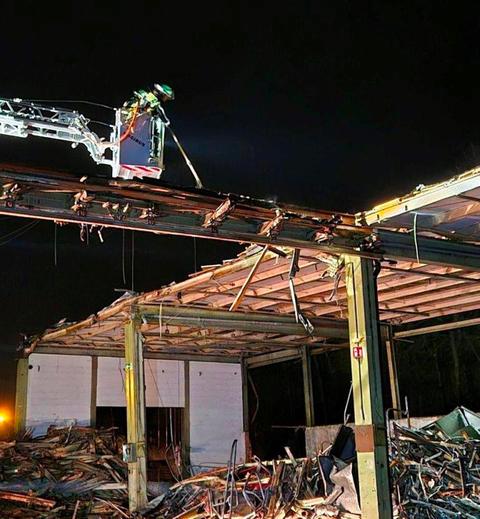 Ausgebrannte Industriehalle; Feuerwehrmann löscht aus einem Krankorb; am Boden Trümmer