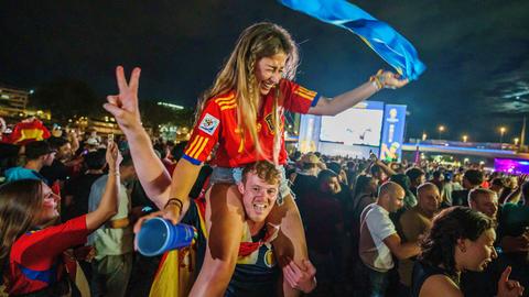 Ein junger Mann trägt eine Frau mit spanischem Trikot auf den Schultern.