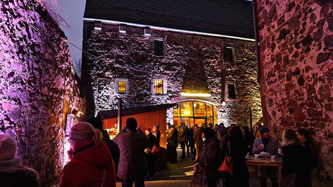 Menschen stehen bei weihnachtlicher Beleuchtung in einem Hof