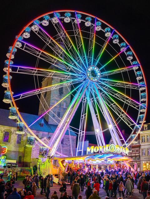 Ein leuchtendes Riesenrad auf einem Volksfest, dunkler Nachthimmel.