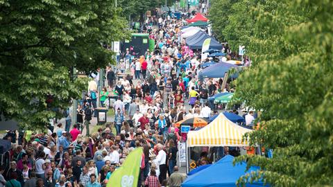 Menschen flanieren an Marktständen entlang