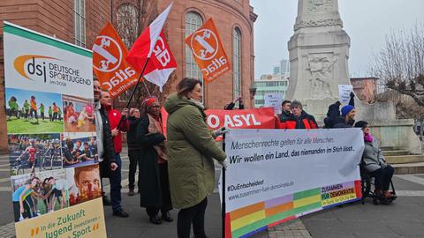 Mehrere Menschen stehen hinter einem Banner mit der Aufschrift:  "Menschenrechte gelten für alle Menschen. Wir wollen ein Land, das niemanden im Stich lässt."