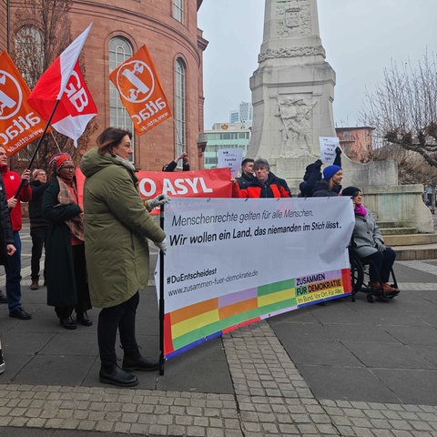 Mehrere Menschen stehen hinter einem Banner mit der Aufschrift:  "Menschenrechte gelten für alle Menschen. Wir wollen ein Land, das niemanden im Stich lässt."