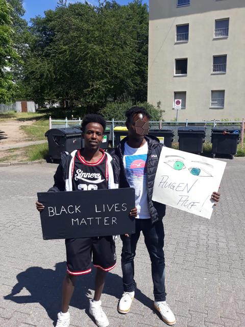 Zwei junge schwarze Männer mit einem Schild, auf dem "Black Lives Matter" steht