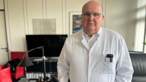 Der Marburger Kardiologe Bernhard Schieffer steht in seinem Arbeitszimmer und schaut besorgt.