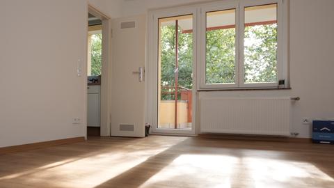 Ein Zimmer mit Holzboden, in das durch ein Fenster Sonnenlicht fällt