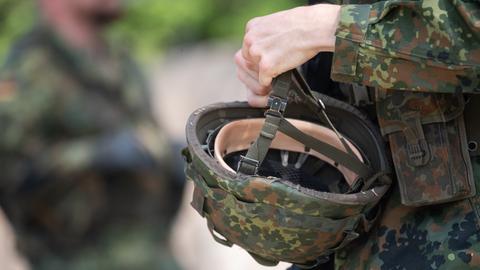 Ein Reservist hält den Helm seiner Uniform in der Hand