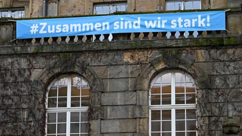 "#zusammen sind wir stark!" steht auf einem Transparent an der Fassade des Kassler Rathauses. Der Kampf gegen das Coronavirus bestimmt mit immer drastischeren Auswirkungen das öffentliche Leben in Hessen. 