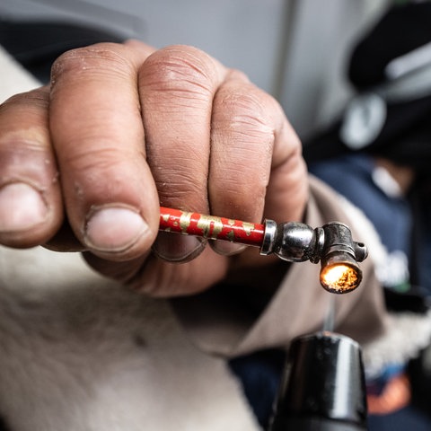 Eine Hand mit schmutzigen Fingernägeln Zündet eine Crackpfeife an