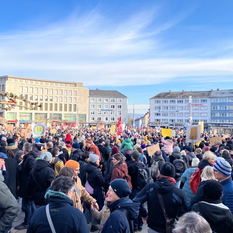 Menschenmenge mit Plakaten auf einem großen Platz