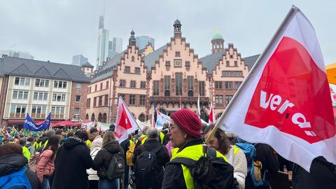 Demonstranten auf dem Frankfurter Römer. Im Vordergrund hält ein Teilnehmer eine rote Verdi-Fahne.