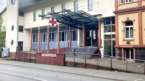 Krankenhausgebäude von außen. Vor der Treppe steht ein Schild "DRK Krankenhaus". Über dem Eingang ein großes rotes Kreuz auf weißem runden Grund