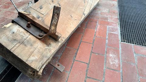 Ein Holzträger liegt mit einer verbogenen Stahlstange auf dem Boden.