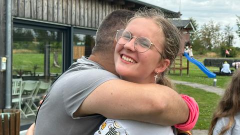 Ukrainischer Pfarrer umarmt junges Mädchen, das in die Kamera lächelt