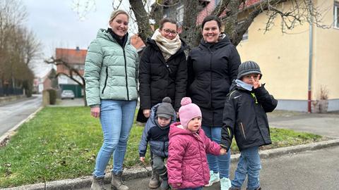 Auf einer Auffahrt in einem Dorf stehen mehrere Frauen und Kinder