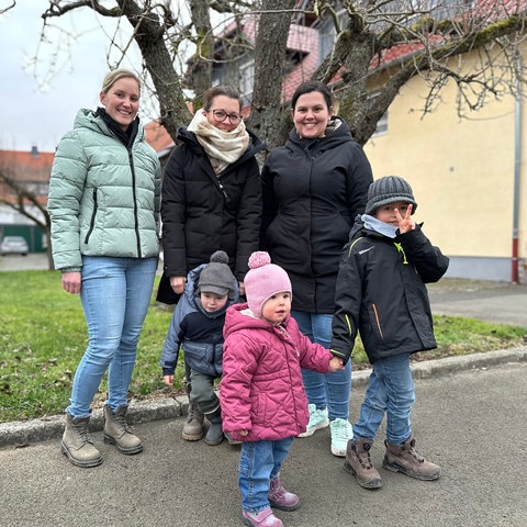 Auf einer Auffahrt in einem Dorf stehen mehrere Frauen und Kinder