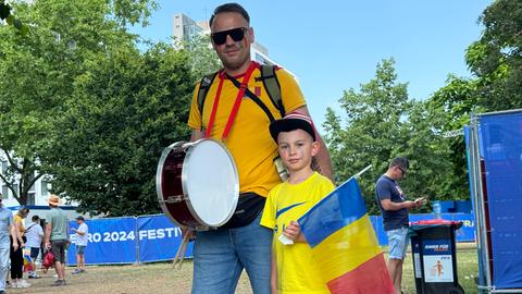 Fan Zone am Main: Ein mann mit einer Trommel, daneben sein Sohn mit einer Rumänienflagge