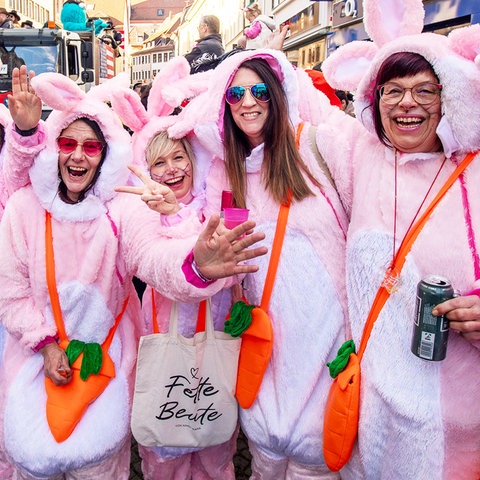 Mehrere Frauen im rosa Kaninchen-Kostüm postieren lachend für die Kamera.