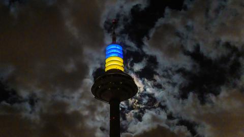 Die Spitze des Frankfurter Fernsehturms bei Nacht in Blau und Gelb beleuchtet