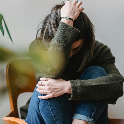 Eine Frau sitzt auf einem Sessel und rauft sich die Haare