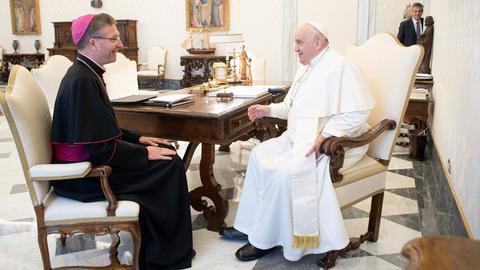 Zwei Männer, der Papst und ein Bischof, sitzen sich in einem Büro gegenüber.