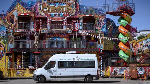 Zur Schule umgebautes Wohnmobil steht vor einem Zirkus