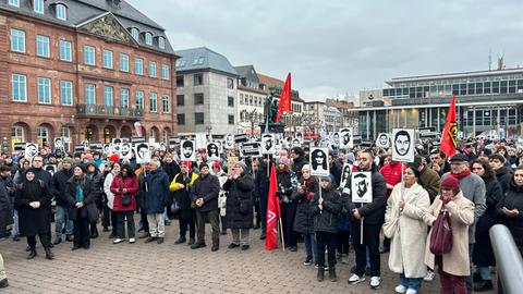 Demonstrierende mit Banner, auf denen Gesichter und Namen der Anschlagsopfer zu erkennen sind