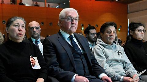 Bundespräsident Steinmeier sitzt zwischen zwei Angehörigen der Opfer des Anschlags von Hanau