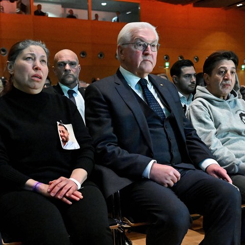 Bundespräsident Steinmeier sitzt zwischen zwei Angehörigen der Opfer des Anschlags von Hanau