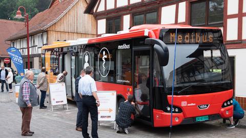 Ein sogenannter Medibus, eine Arztpraxis auf Rädern, steht in einem hessischen Dorf. Menschen begutachten das Fahrzeug.