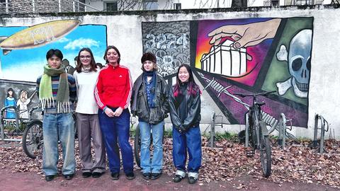 David, Sarah, Carla, Eva und Toyah vor einem Graffito auf dem Schulhof der Justus-Liebig-Schule in Darmstadt.