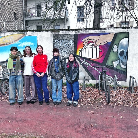 David, Sarah, Carla, Eva und Toyah vor einem Graffito auf dem Schulhof der Justus-Liebig-Schule in Darmstadt.