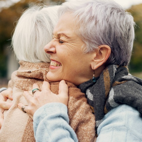 Zwei ältere Frauen umarmen sich fest.