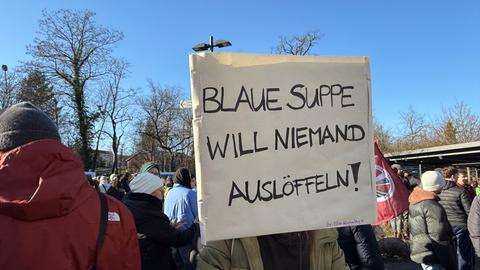 Demonstrantin hält weißes Plakat mit Aufschrift: "Blaue Suppe will niemand auslöffeln!"