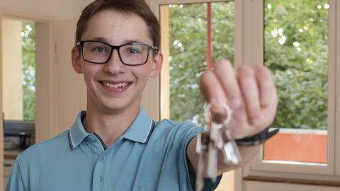 Ein Jugendlicher (16 Jahre) mit Brille und einem hellblauen Poloshirt hält einen Schlüsselbund in die Kamera