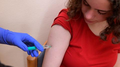 Ein Mädchen im roten T-Shirt bekommt eine Impfung.