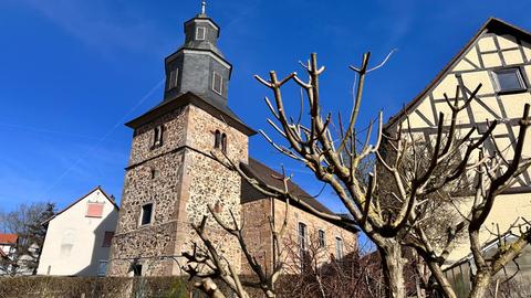 Die Kirche in Wattenbach steht zwischen zwei Häusern und Gärten