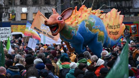 Menschen stehen beim Klimastreik von Fridays for Future vor der Alten Oper um ein brennendes Känguru der Umweltorganisation Greenpeace mit den Erdteilen und der Aufschrift "Klima ist nicht verhandelbar".