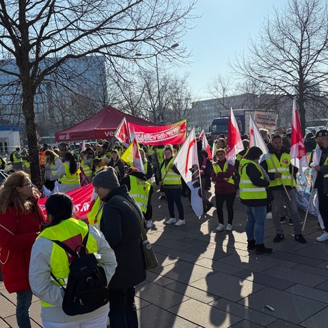 Dutzende Menschen mit Warnwesten und Verdi-Fahnen stehen versammelt