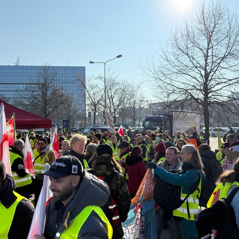 Dutzende Menschen mit Warnwesten und Verdi-Fahnen stehen versammelt.