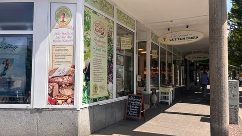 Schaufenster eines Ladens an einer Straßenecke, darin hängen Plakate mit Schrift und Fotos von Brotlaiben, auf dem Schild vor dem Eingang steht "Gut zum Leben"