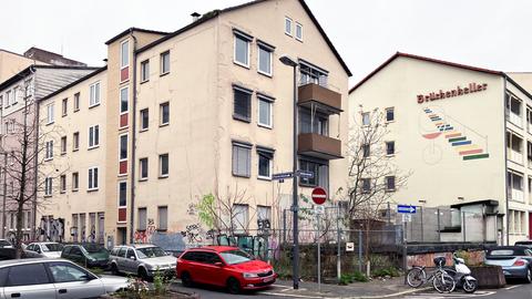 Mehrstöckiges Wohnhaus in einem Wohngebiet mit Graffiti an der Fassade, auf der Straße parken mehrere Autos.