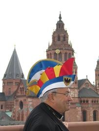 Kardinal Karl Lehmann im Jahr 2004 mit der Ehrenmütze des Aachener Karnevalsvereins auf dem Kopf vor dem Mainzer Dom.