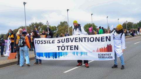 Demonstrierende mit einem Banner "Stoppt fossile Subventionen"