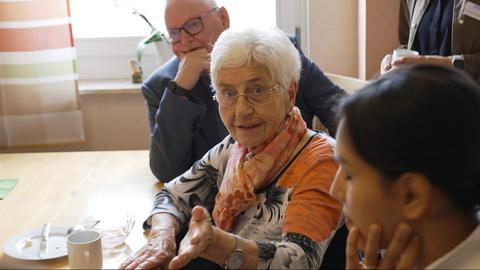 Ältere Dame gestikuliert am Kaffee-Tisch mit der Hand