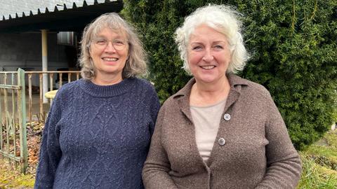 Zwei Frauen mit grauen Haaren lachen in die Kamera